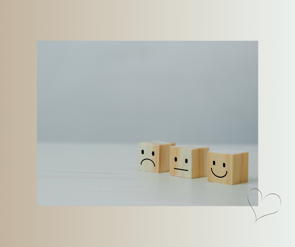 Drei Holzwürfel mit Gesichtsausdrücken: traurig, neutral, fröhlich.