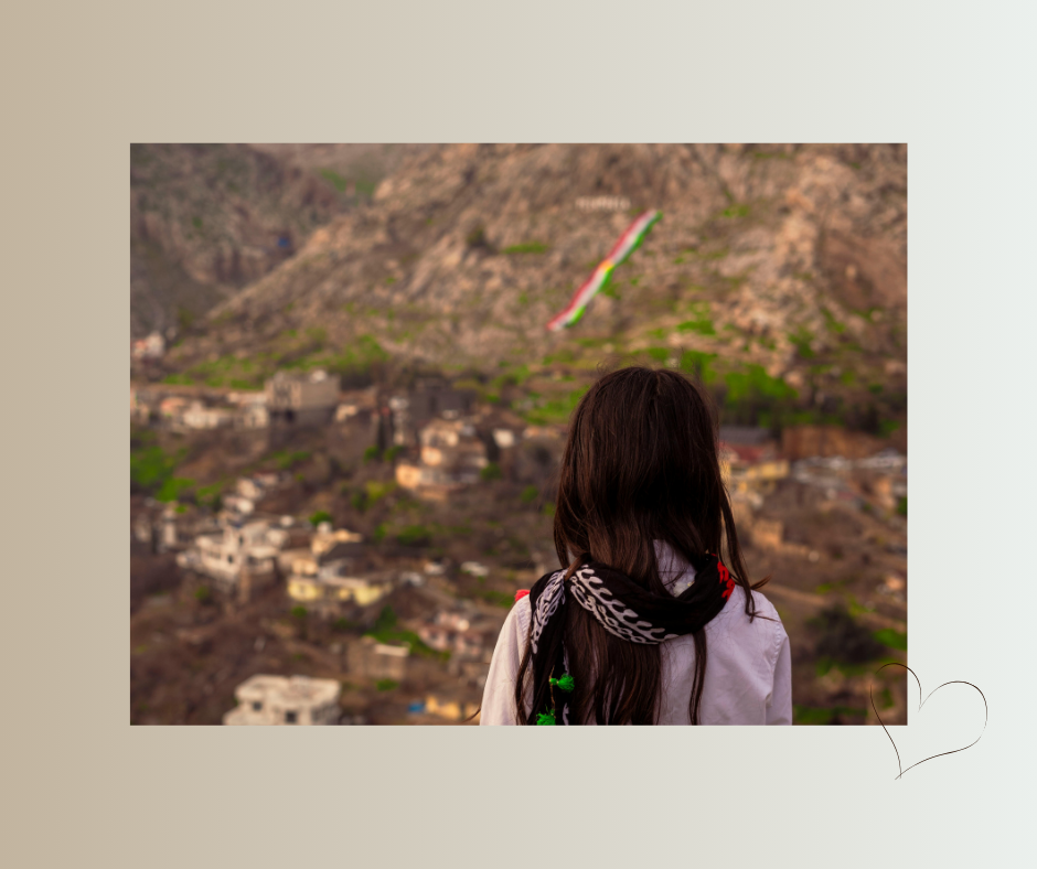 Frau mit langem Haar blickt über ein Tal auf eine Siedlung